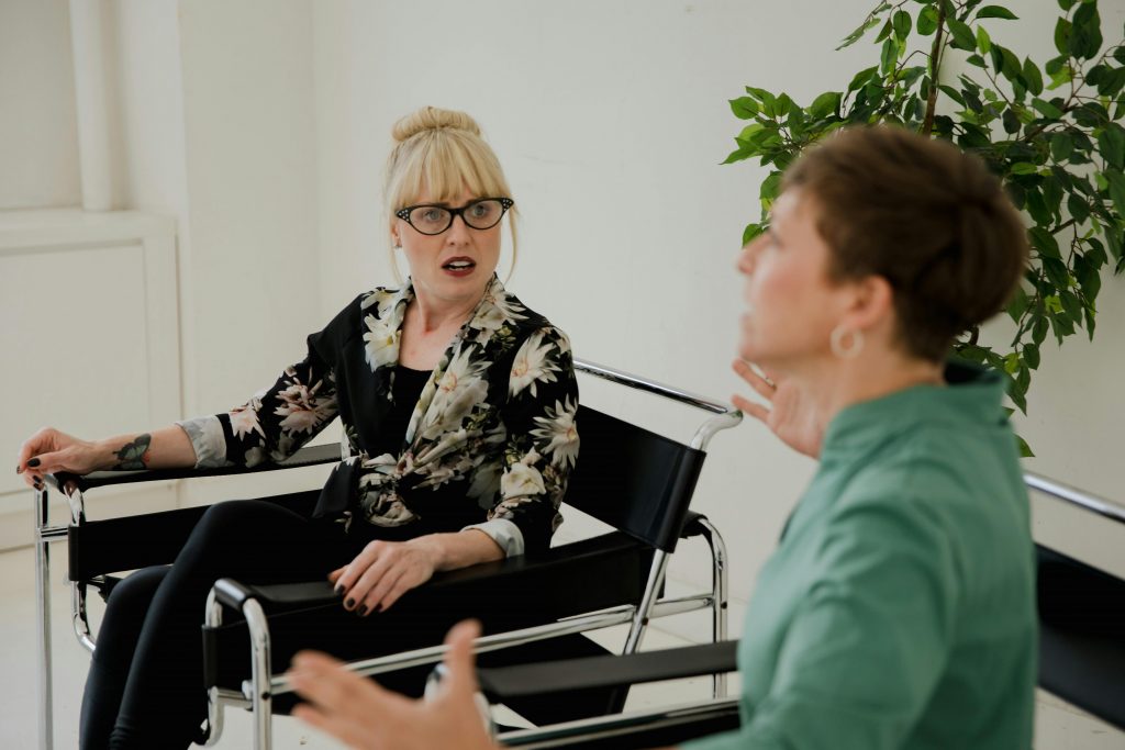 Two women in a professional setting discussing mental health topics indoors.